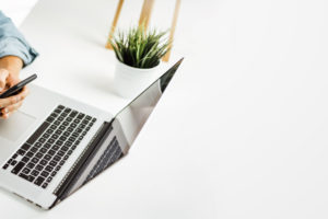 Young man with smartphone in his hands typing message. Close-up. Modern businessman at sunny office. Freelancer at work. Copy space for text