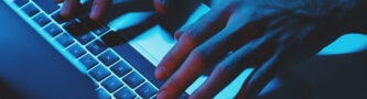 A man Using a laptop computer under blue light.